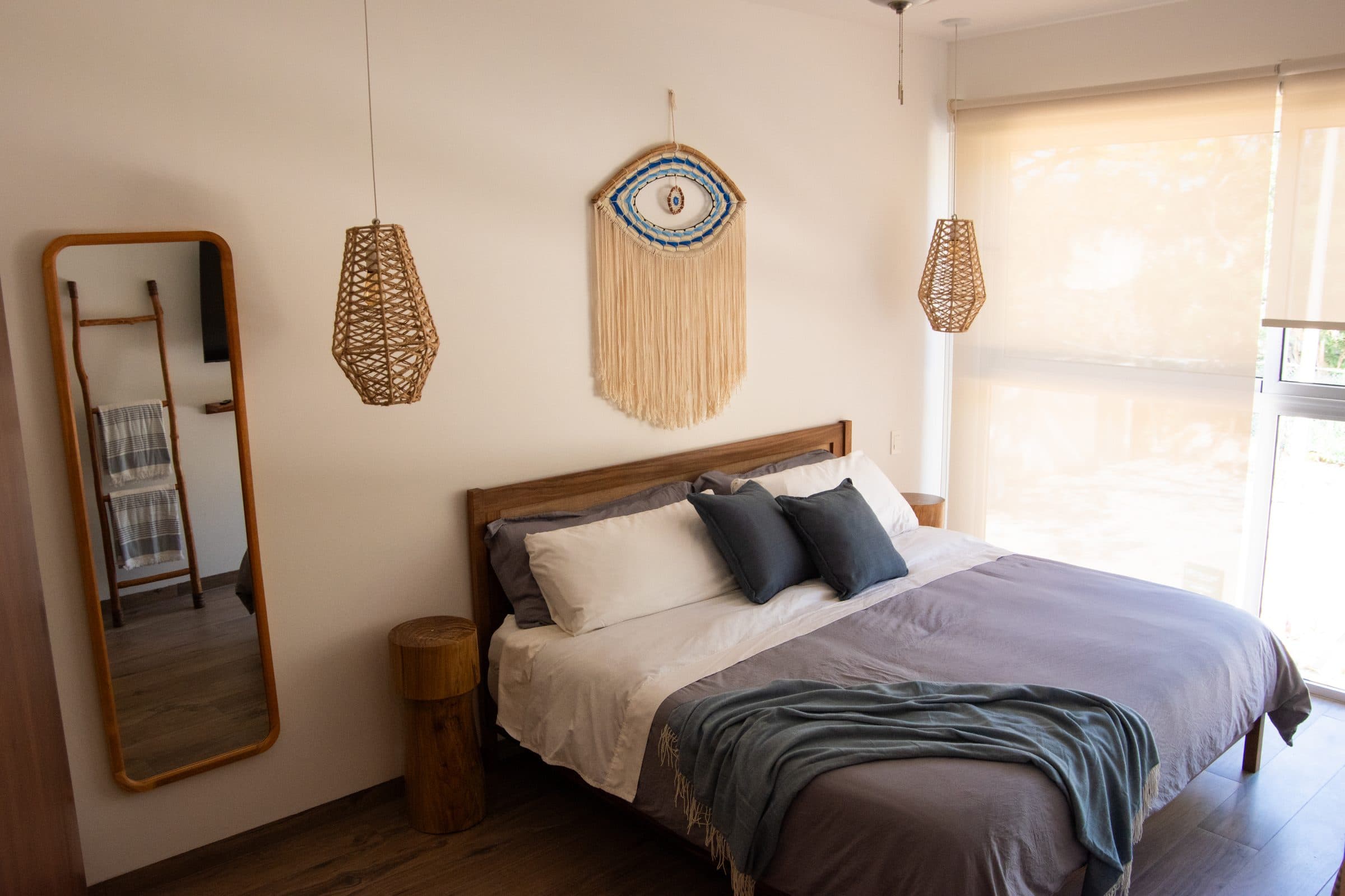 Primary suite with macrame evil eye decor and woven pendant lights at The Leaf Playacar